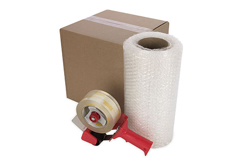 Packing supplies: cardboard box, bubble wrap roll, and packing tape dispenser.
